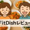 FitDishのお惣菜をお皿に盛り付け、主婦と夫がレビューしているアイキャッチ画像。実写の料理とかわいいイラストを組み合わせたデザイン