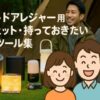 アウトドアガジェットを紹介するキャンプ風景のアイキャッチ画像。背景にはテントとキャンプ用品、前景には好太郎とめぐみのイラストキャラクター、中央にポータブル電源・LEDランタン・ヘッドライトなどが並ぶ。
