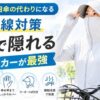 顔まで隠れるUVカットパーカーを着た女性が自転車の横に立つ屋外シーン。大きく「日傘いらない？」のテキストと、UPF50+・フェイスカバー・指穴付きなどの特徴がアイコンで表示されたブログ用アイキャッチ画像。