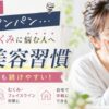 朝起きると顔がパンパンで悩む女性が鏡を見ながら頬に手を当てている様子。忙しい人でも続けやすい5分美容習慣や顔のむくみ対策、フェイスラインケアについて紹介するイメージ画像。